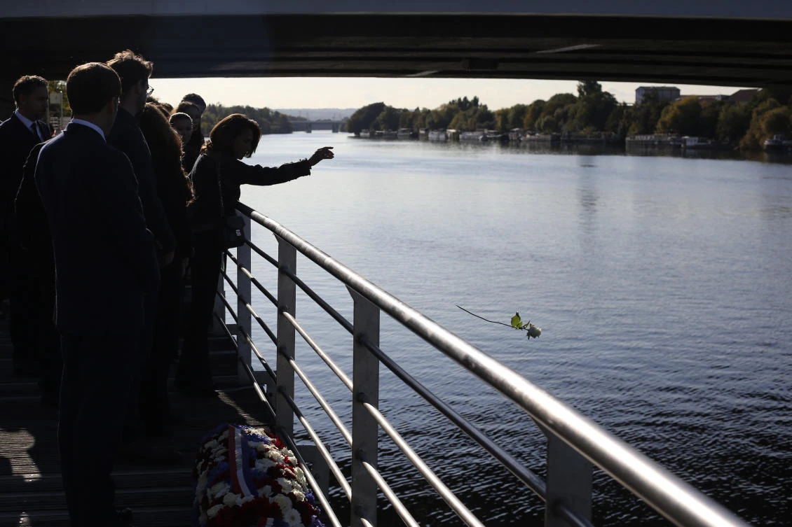 A guest throws a rose into the Seine river after French President Emmanuel Macron laid a wreath near the Pont de Bezons (Bezons bridge) Saturday, Oct. 16, 2021 in Colombes, near Paris. (AP)