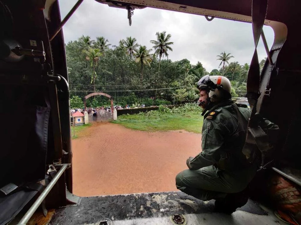 This photograph shows a navy person looking from their helicopter on a mission to distribute relief material to flood affected people at Koottickal in Kottayam district, southern Kerala state, India, Sunday, Oct.17, 2021. (AP)