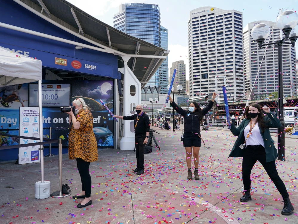 Staff members cheer to celebrate the re-opening of SEA LIFE Sydney Aquarium to visitors following an extended closure due to coronavirus disease. (Reuters)