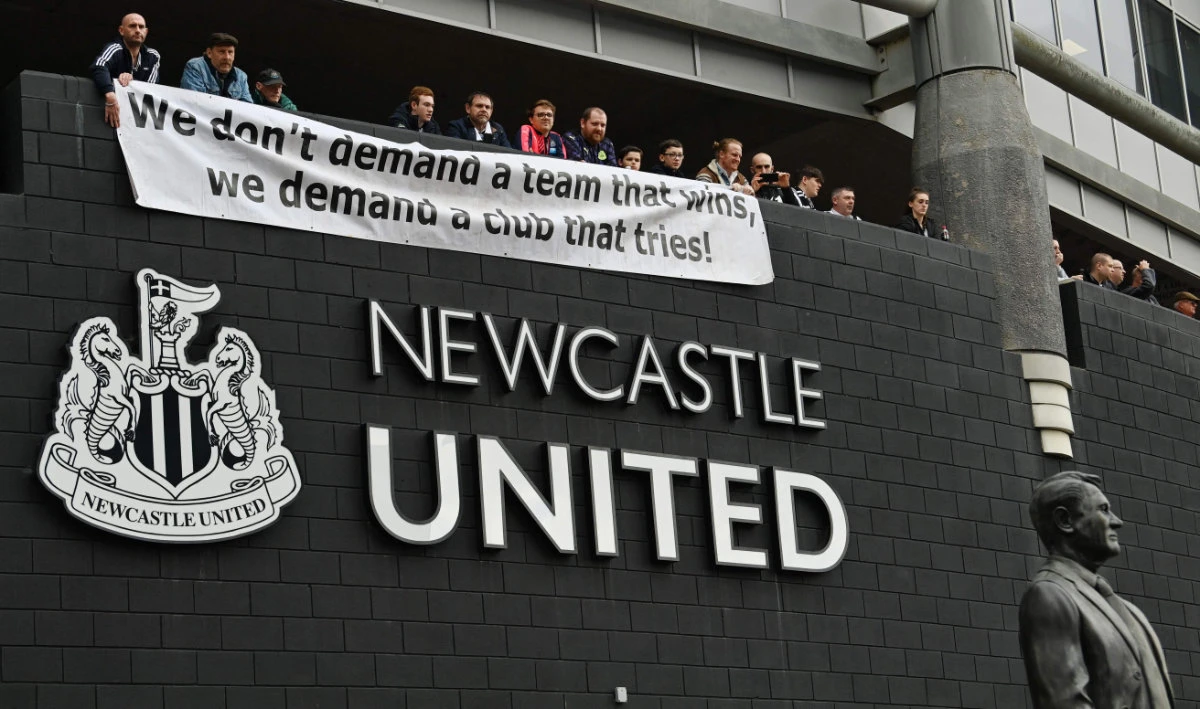 Newcastle United fans stand behind a banner as they arrive at St. James' Park in Newcastle-upon-Tyne, England on Oct. 17, 2021 for the EPL football match with Newcastle United and Tottenham Hotspur. (AFP)