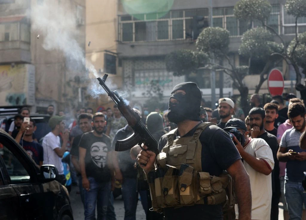 A member of Lebanon's Hezbollah movement fires his gun during the funeral of some of their members who were killed during clashes in the capital Beirut's southern suburbs, on October 15, 2021 (AFP via Getty Images)