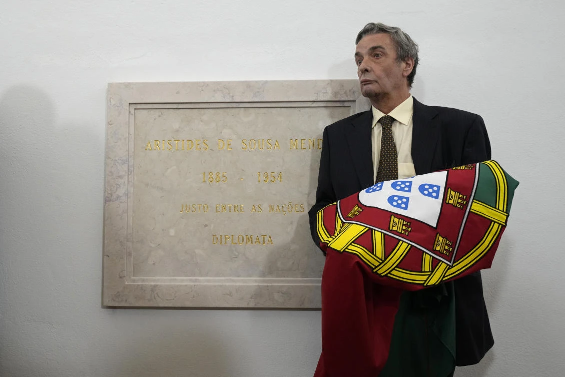 Alvaro de Sousa Mendes holds the Portuguese flag presented to him next to the plaque honoring his grandfather, Aristides de Sousa Mendes, who during World War II helped save thousands from Nazi persecution, on Tuesday. (AP)