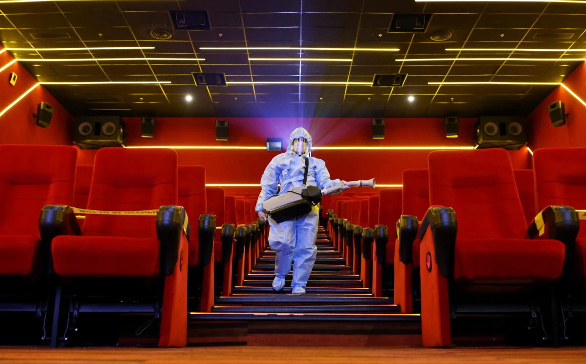 A worker wearing personal protective equipment (PPE) sanitizes seats inside a movie theatre ahead of its reopening, amidst the outbreak of the coronavirus disease (COVID-19), in Mumbai, India, October 20, 2021. (Reuters)