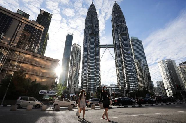 People wearing protective masks cross a street in front of Petronas Twin Towers, amid the coronavirus outbreak in Kuala Lumpur, Malaysia, on January 11, 2021. (REUTERS/File)