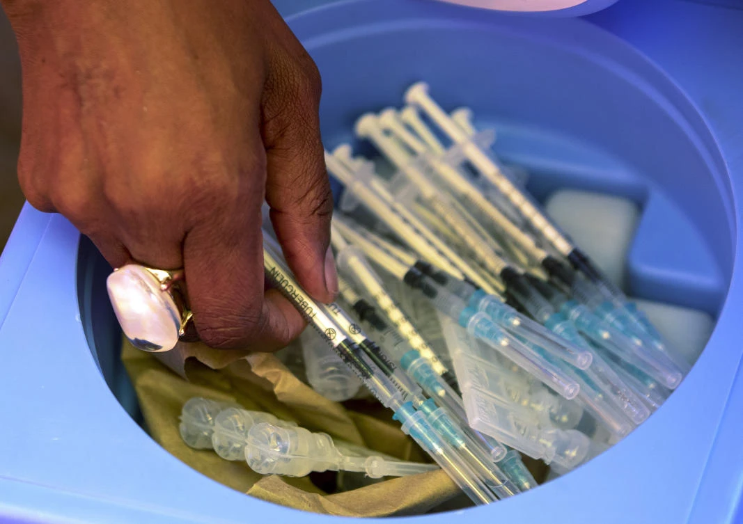 A health worker picks syringes as seniors get vaccinated with the first dose of the Pfizer coronavirus vaccine at a drive-thru vaccination center in Johannesburg, South Africa. (AP)