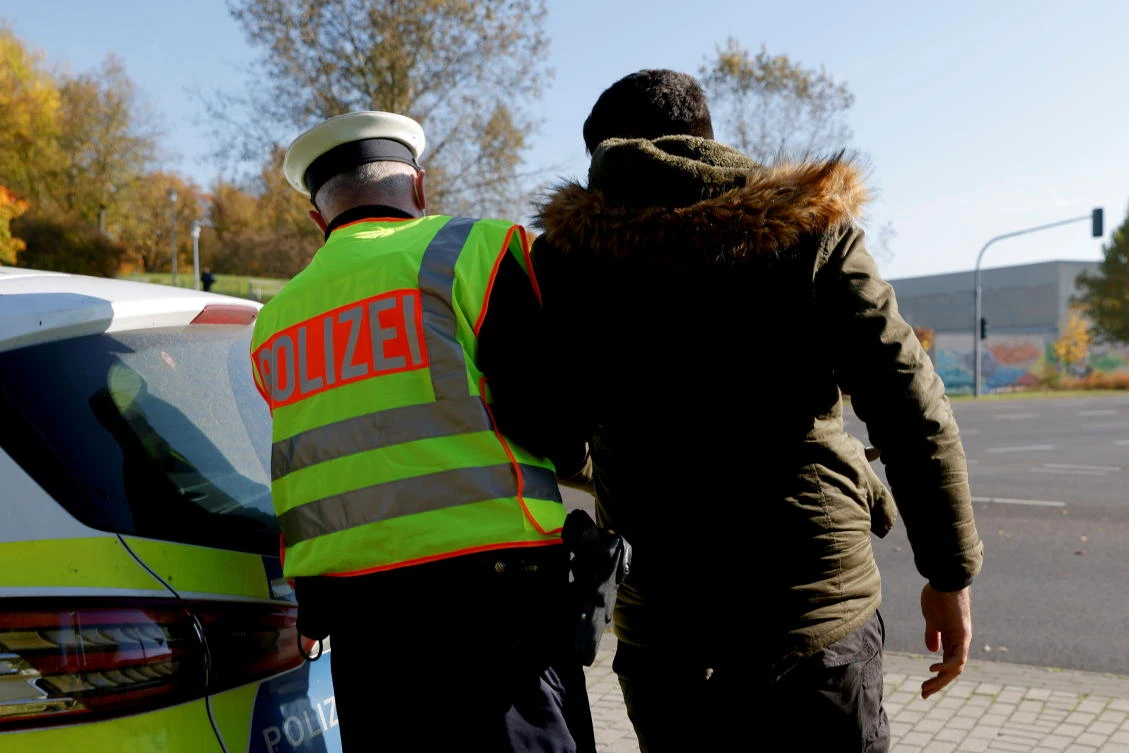 A German police officer detains a migrant, reportedly coming from Iraq through Belarus and Poland, during a patrol near the German-Polish border, in Frankfurt on Thursday. (Reuters)