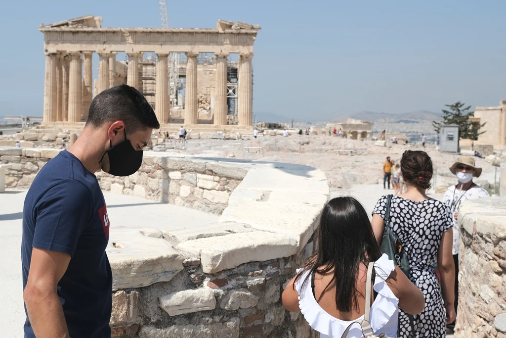 Tourists wearing facemasks stand in front of the Parthenon temple at the Acropolis in Athens. (Shutterstock)
