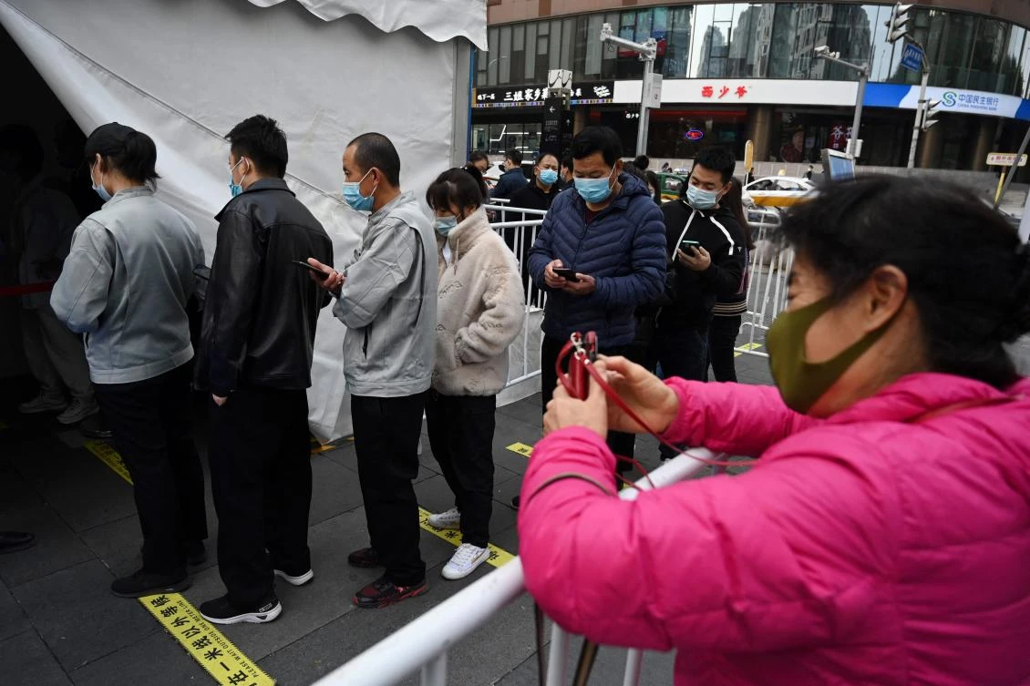 People line up to get a booster shot of the Covid-19 coronavirus vaccine in a tent set up outside a shopping mall in Beijing on November 1, 2021. (AFP)
