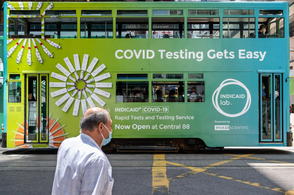 A double-deck tram runs covered with a government advert asking the public to get tested for Covid-19 virus is seen in Hong Kong. (Getty)