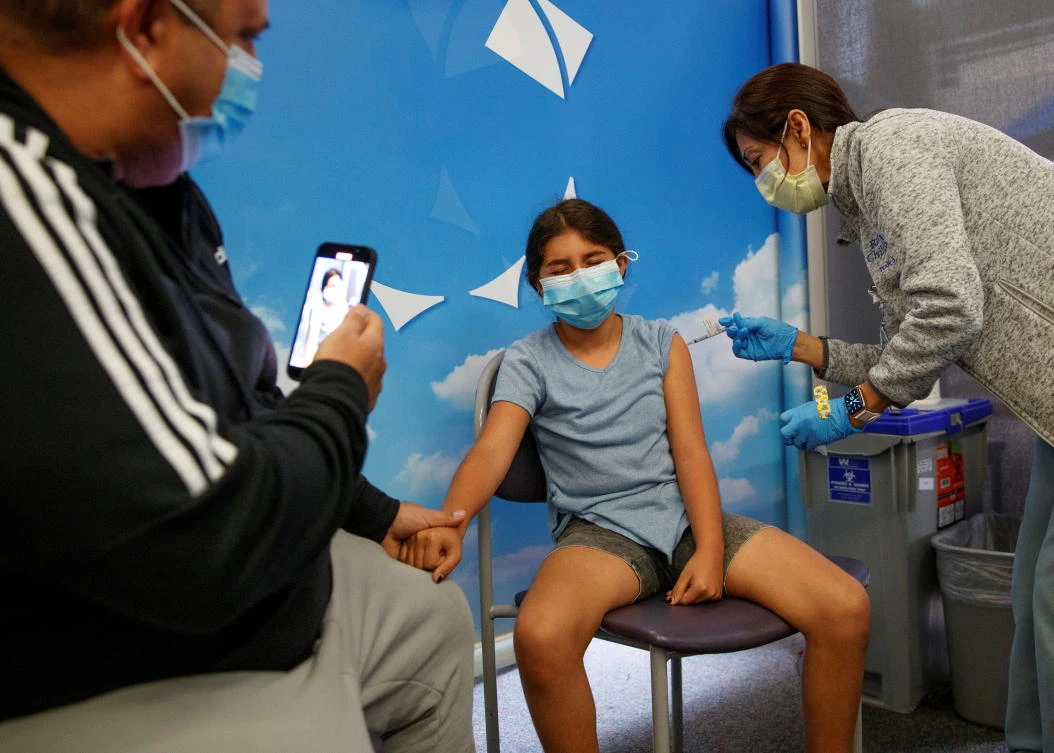 Ten year-old Spraya Yamini holds her father’s hand as she receives Pfizer-BioNTech coronavirus vaccine at Rady’s Children’s hospital vaccination clinic in San Diego, California on Wednesday. (Reuters)