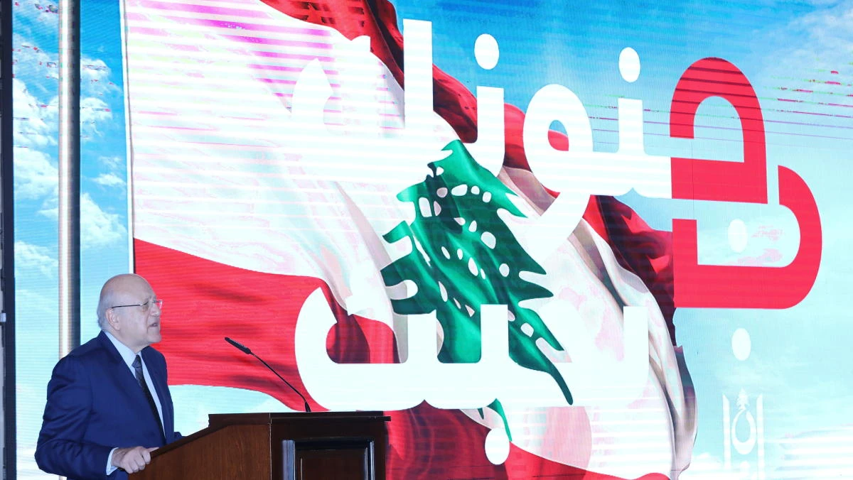 Lebanese Prime Minister Najib Mikati speaks as he stands near a slogan that reads ‘We love you in your madness’ displayed on a screen at the government palace in Beirut on Thursday. (Reuters)