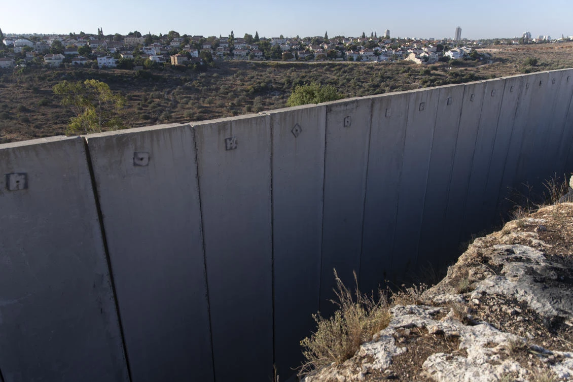 The Israeli settlement of Hashmona'im is seen behind a section of Israel's separation barrier, in the West Bank village of Nilin, west of Ramallah, Sunday, Nov. 7, 2021. (AP)