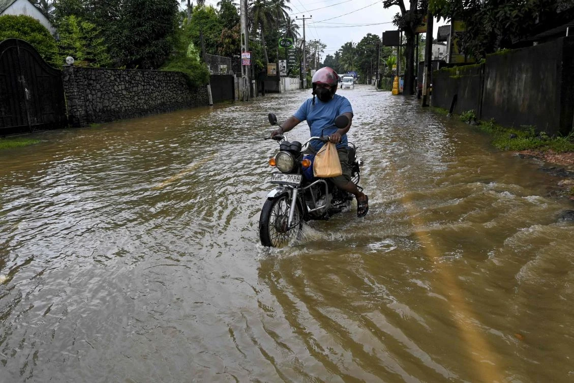 A motorcyclists wade through a flooded street after heavy monsoon rains at Biyagama, on the outskirts of Colombo on November 9, 2021. (AFP)