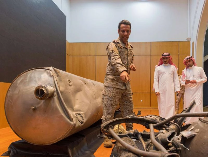Colonel Turki Al-Malki poiints to the debris of a missile fired by the Houthis in a previous attack. (File/AFP)