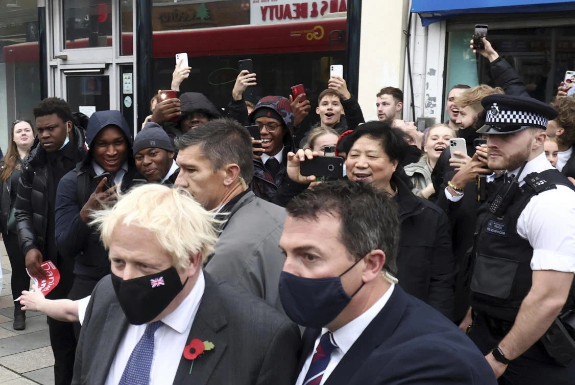 Britain’s Prime Minister Boris Johnson is photographed by the crowd as he leaves after visiting a COVID-19 vaccination center in a pharmacy in south east England on Friday during a visit to Old Bexley and Sidcup. (AP)