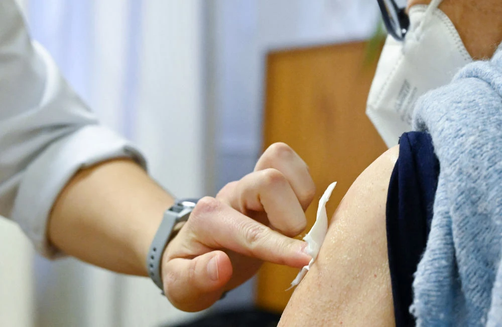 Medical personal holds a swap on the arm of a woman after her vaccination in Stuttgart, southern Germany, on November 16, 2021. (AFP)