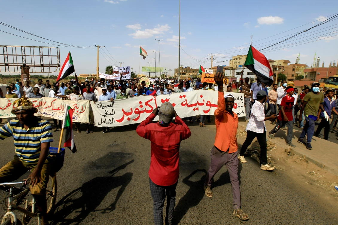 Protesters carry a banner and national flags as they march against the Sudanese military’s recent seizure of power and ousting of the civilian government in Khartoum. (Reuters)