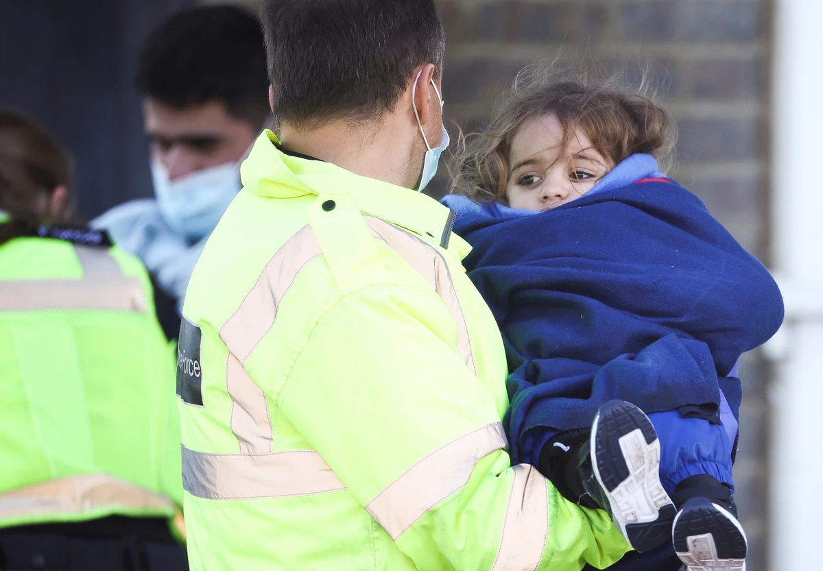 A migrant child is carried by Border Force staff into Dover harbour after crossing the channel in Dover, Britain, November 18, 2021. (Reuters)