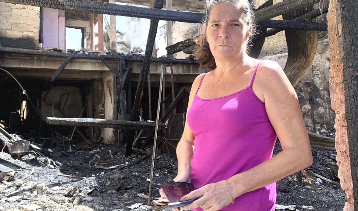 Emilie holds her burned passport in her charred home in Pointe-a-Pitre, Guadeloupe island, where protests over COVID-19 restrictions erupted into rioting. (AFP)