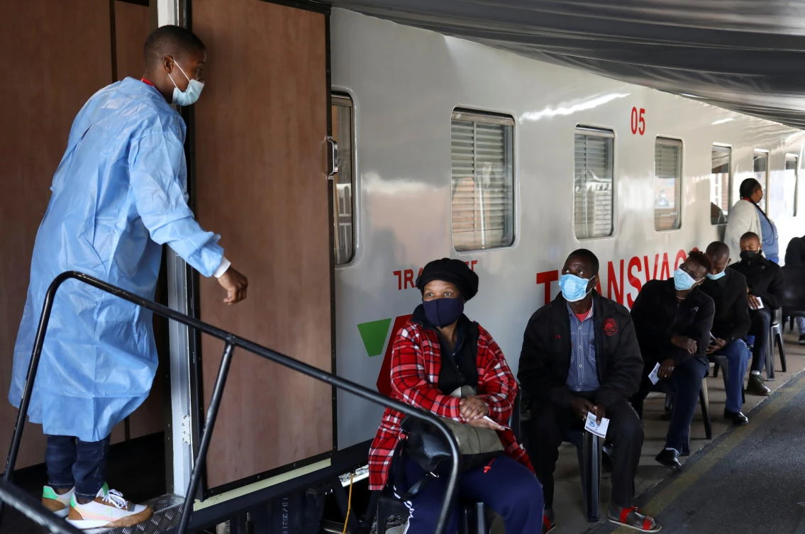 A health worker talks to people waiting to register next to Transvaco COVID-19 vaccine train, after South Africa’s rail company Transnet turned it into vaccination center to help the government speed up its vaccine rollout. (Reuters)