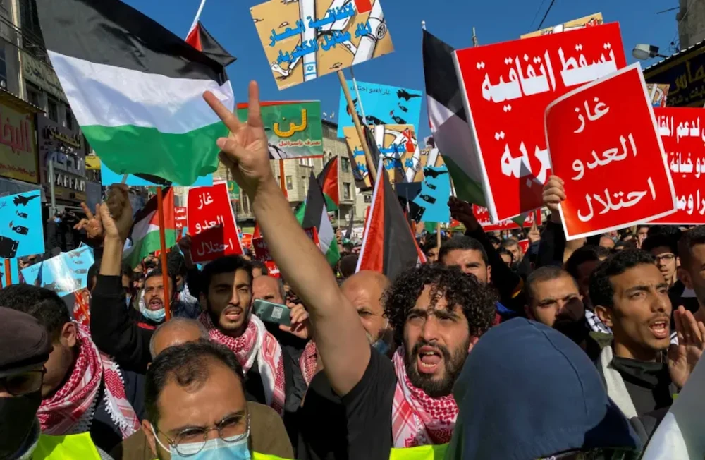Jordanians carry flags and placards as they demonstrate against the declaration of intent for water-for-energy deal. (Reuters)