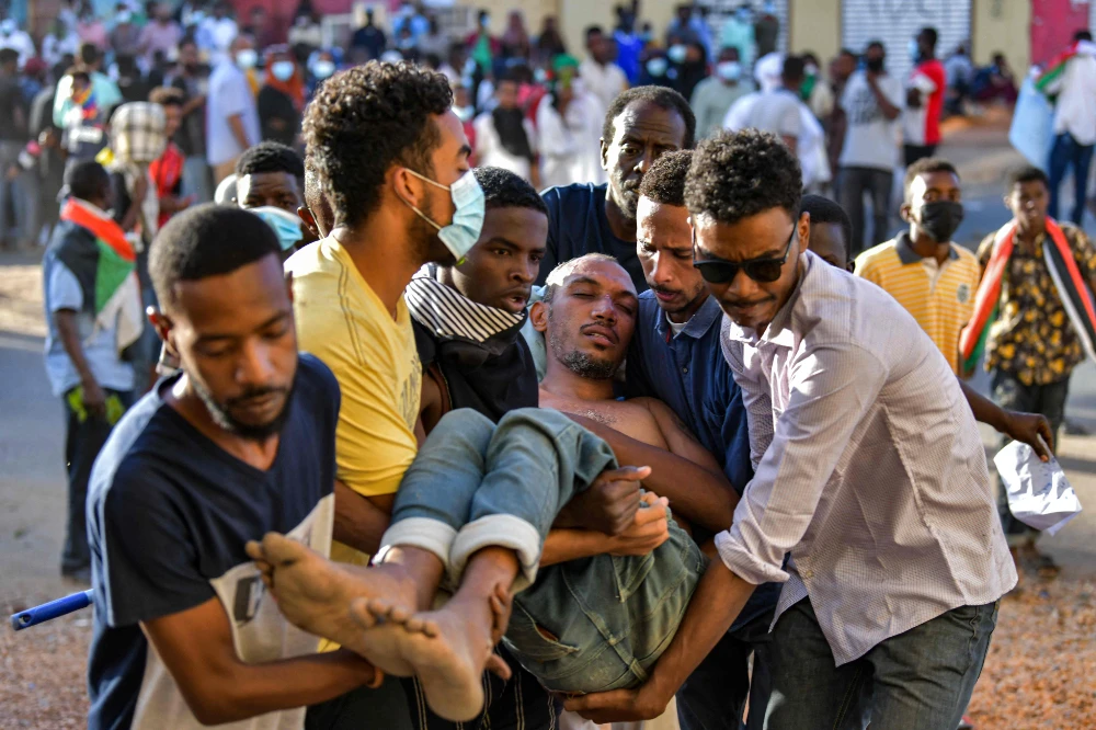 A wounded Sudanese anti-coup protester is carried away by comrades during a demonstration in the “Street 40” of Omdurman. (AFP)
