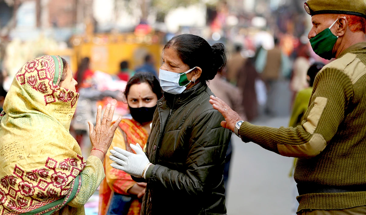 A policewoman requests pedestrians to get tested for COVID-19 at a nearby testing booth in Jammu. India has so far fully vaccinated some 35% of its population. (AP)