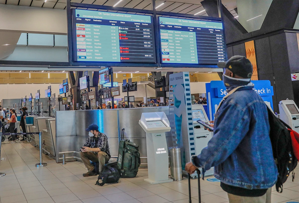 A passenger holds his mobile phone while looking at an electronic flight notice board displaying cancelled flights at OR Tambo International Airport in Johannesburg, South Africa, on November 27, 2021. (AFP)