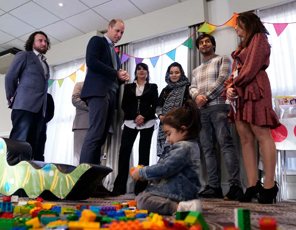 Britain's Prince William, Duke of Cambridge (2nd L) watches young children playing during a visit to a hotel in Leeds, northern England on November 30, 2021 which is being used to accommodate refugees evacuated from Afghanistan. (AFP)
