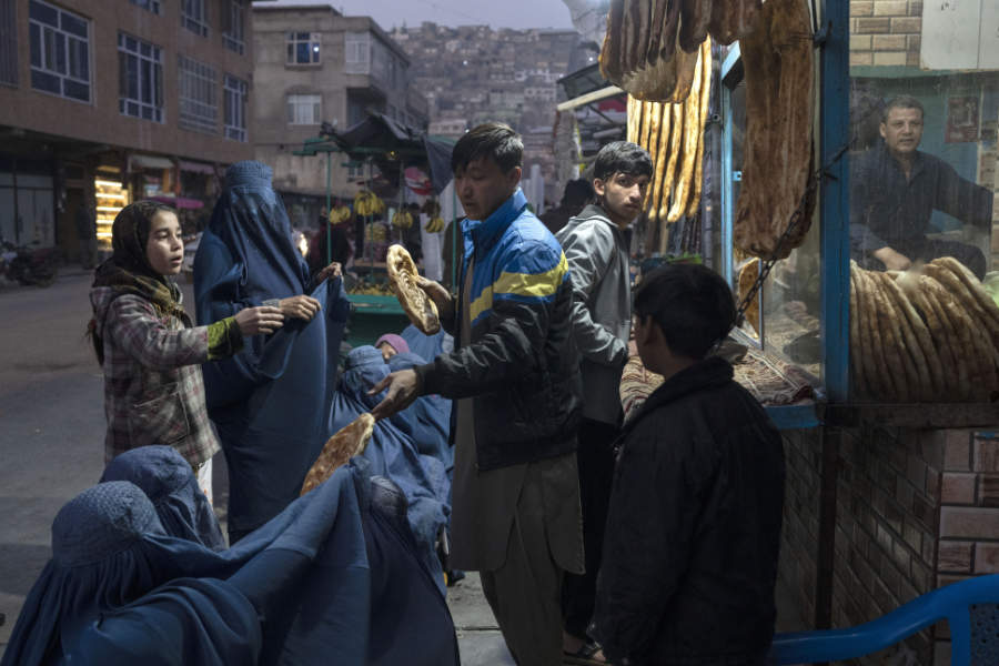 A man distributes bread to Burka-wearing Afghan women outside a bakery in Kabul, Afghanistan, Thursday, Dec, 2, 2021. (AP)