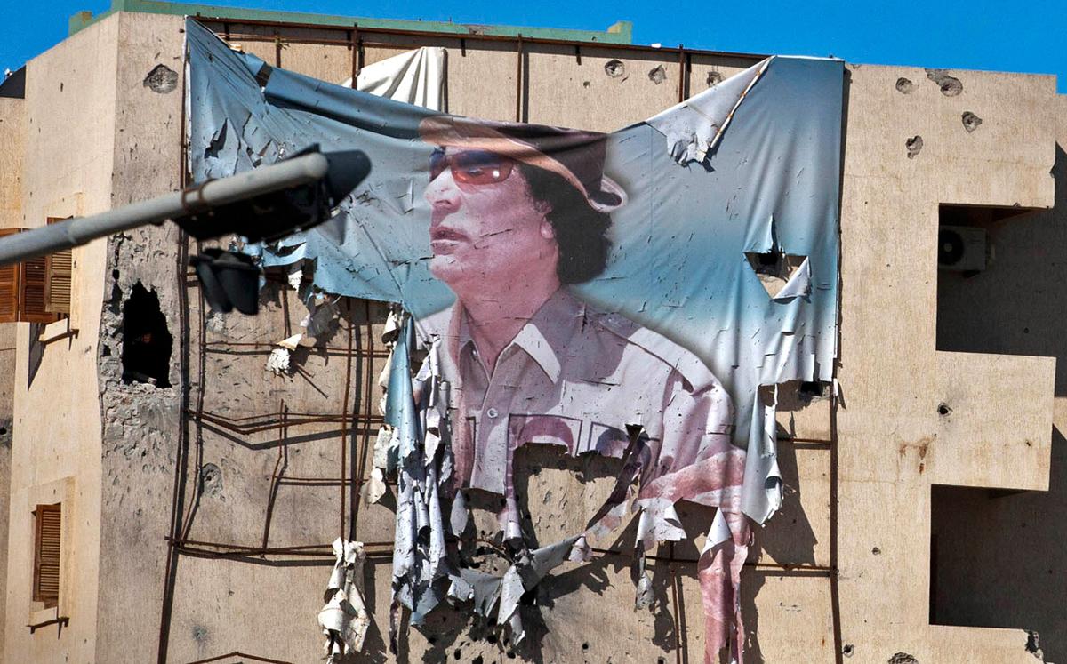 A tattered banner featuring Muammar Qaddafi hangs from a building in Sirte, Libya, Oct. 12, 2011. (Getty Images)