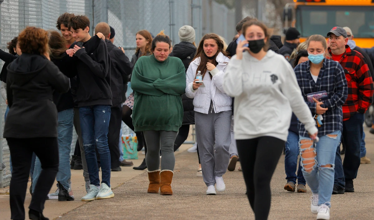 Parents walk away with their kids from the Meijer's parking lot in Oxford where many students gathered following an active shooter situation at Oxford High School, Tuesday, Nov. 30, 2021, in Oxford, Mich. (AP)