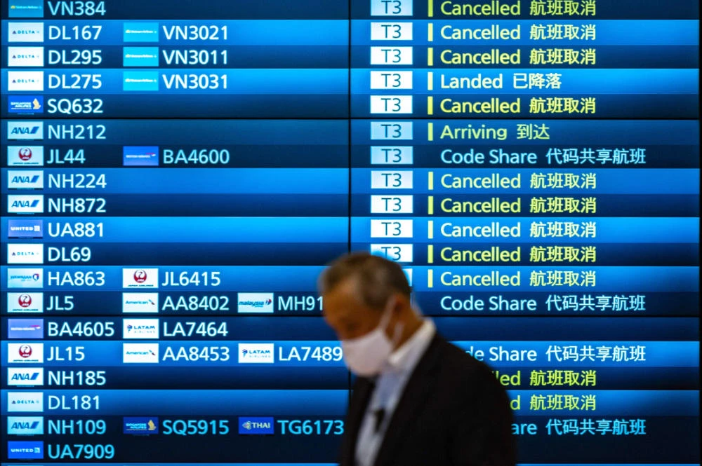 A man walks past an arrivals board showing cancelled flights at Tokyo's Haneda international airport on November 30, 2021. (AFP)