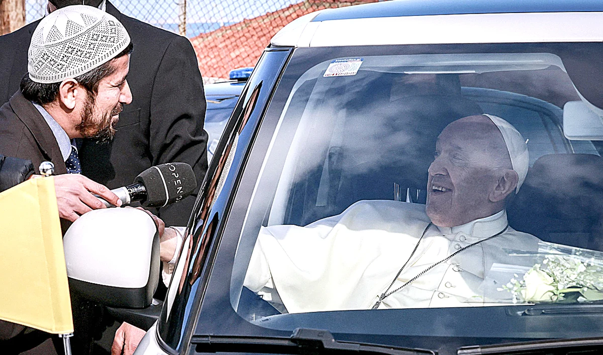 Pope Francis, right, speaks with an imam as he leaves in a car after meeting refugees in Mytilene on the island of Lesbos on Sunday. (AFP)