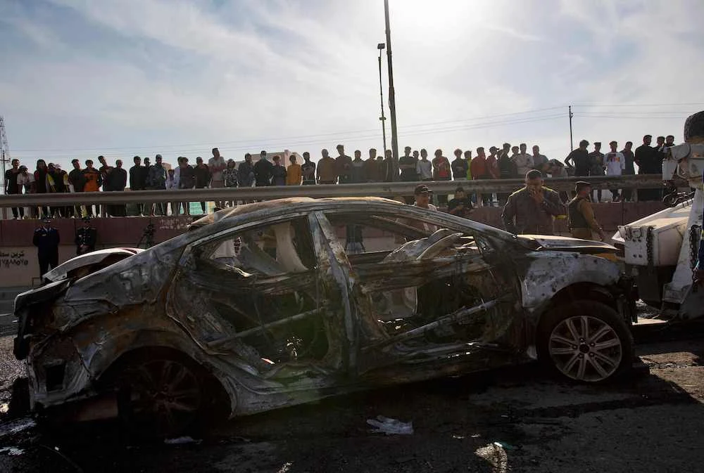 Above, bystanders look at a destroyed car in the southern Iraqi city of Basra after a motorcycle bombing on Dec. 7, 2021 which was claimed by Daesh. (AFP)