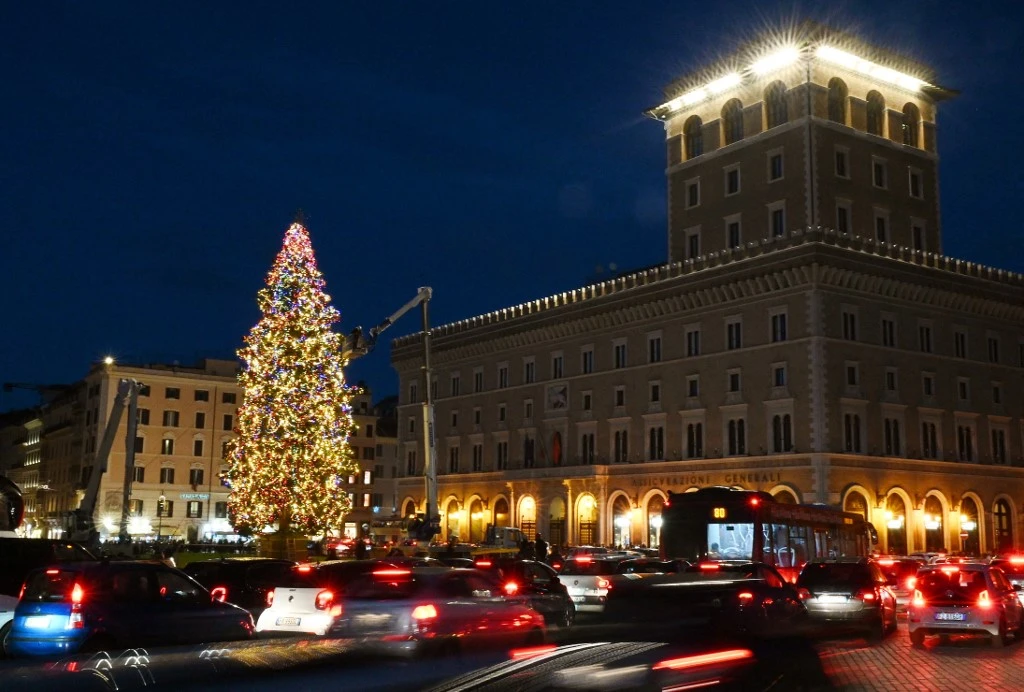 Workers put up decorations on the annual Christmas tree on Dec. 05, 2021 at Piazza Venezia in central Rome. (AFP)