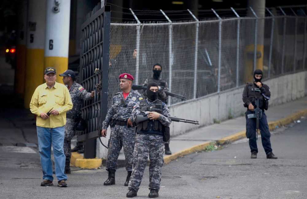 A group of Venezuelan political police officers, SEBIN, with their faces covered stand on guard at the main door of SEBIN headquarters in Caracas, Venezuela. (AP file photo)