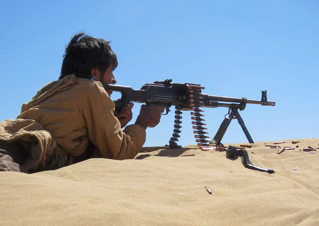 A Yemeni pro-government fighter takes aim from his position during fighting with Huthi rebels on the al-Jawba frontline south of Marib, the last remaining government stronghold in northern Yemen, on December 7, 2021. (Photo by AFP)