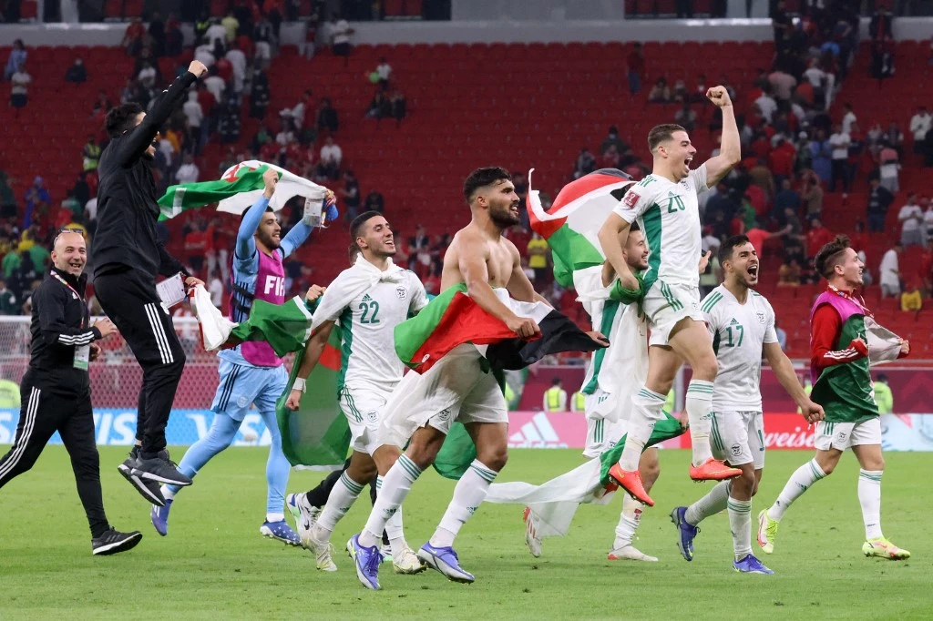 Algeria's players lift national and Palestinian flags as they celebrate their win during the FIFA Arab Cup 2021 quarter final football match between Morocco and Algeria at the Al-Thumama Stadium in the Qatari capital Doha on December 11, 2021. (File/AFP)