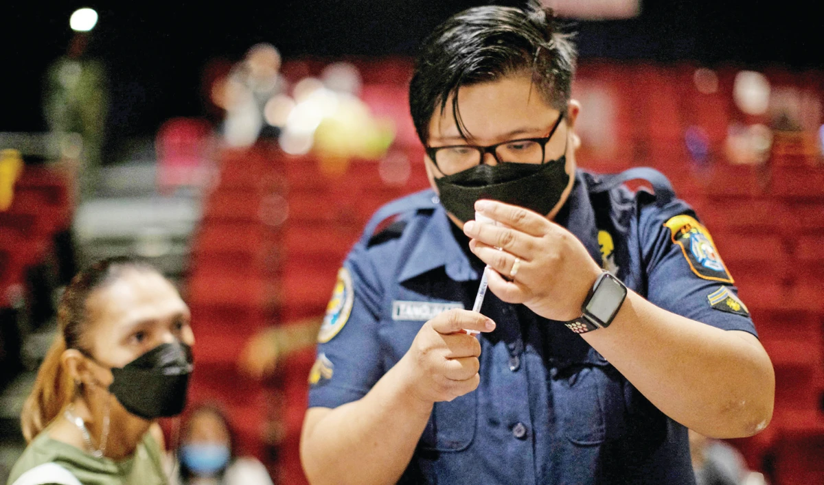 A health worker prepares a dose of vaccine for protection against COVID-19 at a cinema turned into a temporary vaccination site in Manila. (Reuters)