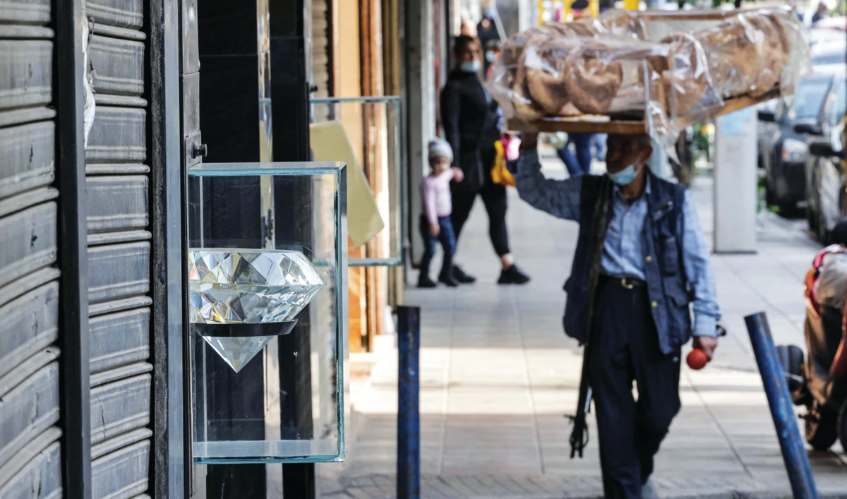 A pastry peddler walks past closed jeweler’ shops in the popular market of the Burj Hammoud neighborhood of Lebanon’s capital Beirut on Tuesday. (AFP)