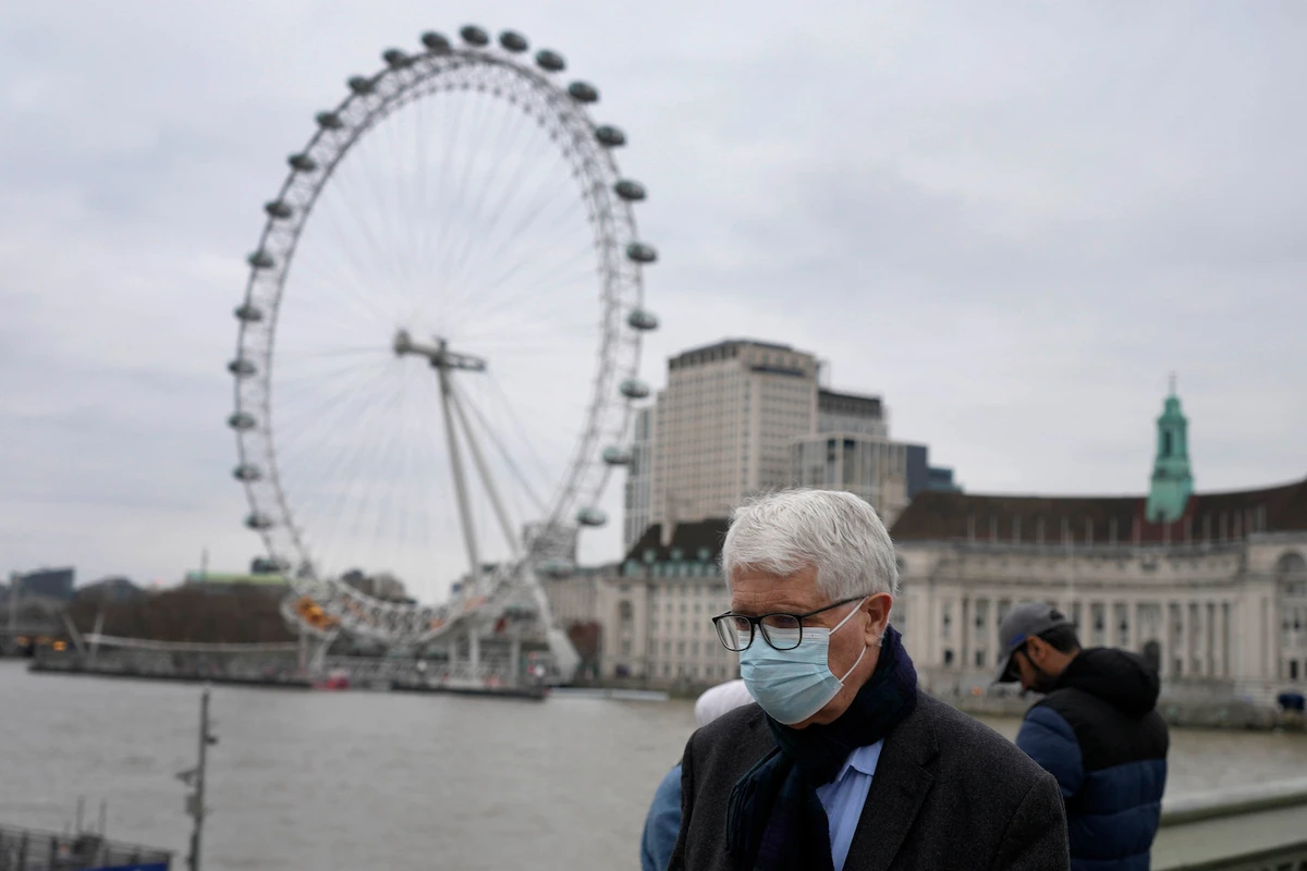 A man wearing a face covering crosses Westminster Bridge in fron of the iconic London Eye in London, Thursday, Dec. 16, 2021. (AP)