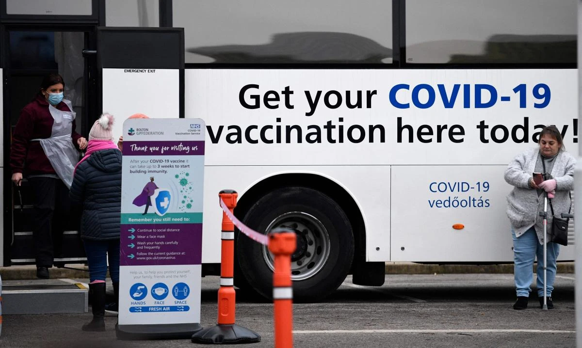 Members of the public wait to receive their Covid-19 vaccine or booster at a NHS (National Health Service) bus outside an Asda Supermarket in the town of Farnworth, near Manchester in north-west England on December 20, 2021. (AFP)