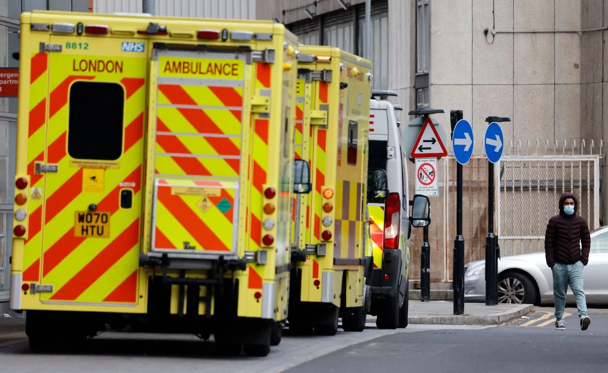 A pedestrian wearing a face covering due to the Covid-19 pandemic walks past ambulances parked outside the Royal London hospital in London on December 20, 2021. (AFP)