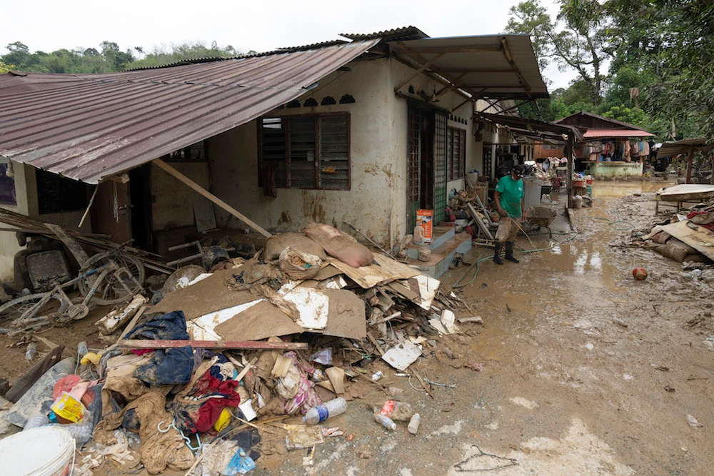 A man clean outside his damaged house following the flooding at Hulu Langat, outskirt of Kuala Lumpur, Malaysia, Wednesday, Dec. 22, 2021. (AP)