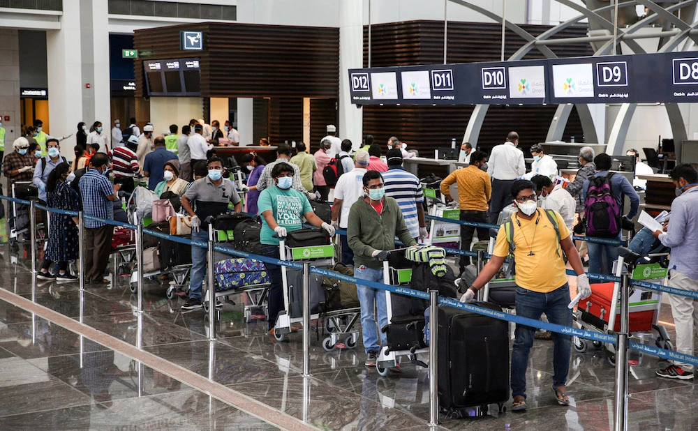 Expats residing in Oman queue with their luggage at the check-in counter at a terminal in Muscat International Airport. (File/AFP)
