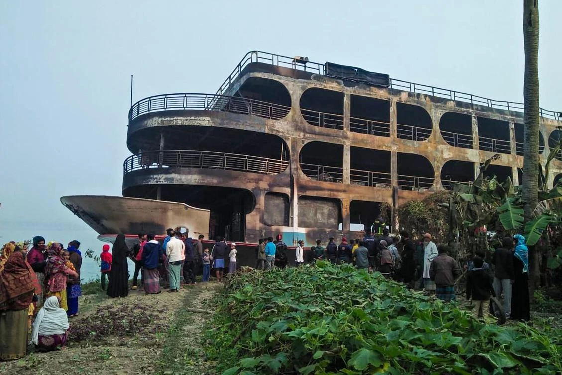 Villagers look at a burnt-out ferry after it caught on fire killing at least 37 people in Jhakakathi, 250 kilometres (160 miles) south of Dhaka, on Dec. 24, 2021. (AFP)