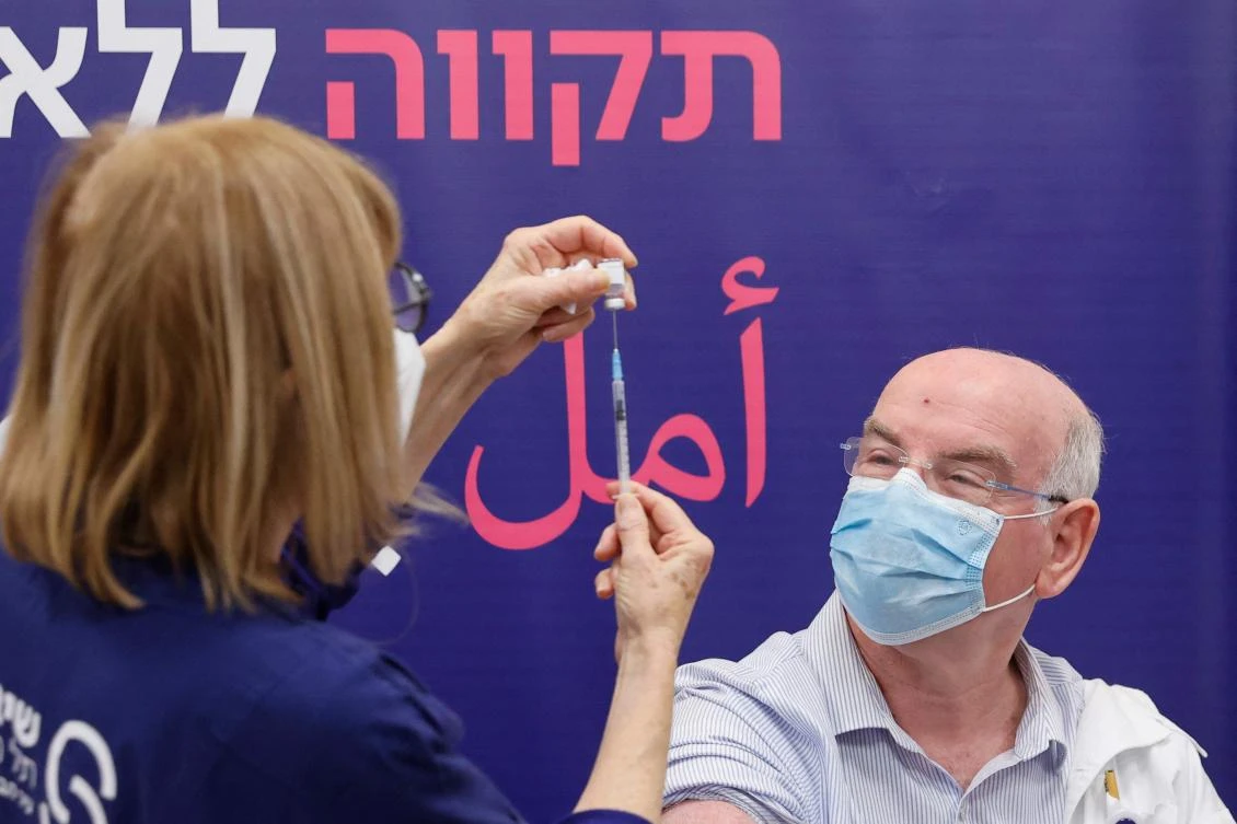 Israeli Professor Jacob Lavee receives a fourth dose of the Pfizer-BioNTech COVID-19 coronavirus vaccine at the Sheba Medical Center in Ramat Gan near Tel Aviv, on December 27, 2021. (AFP)
