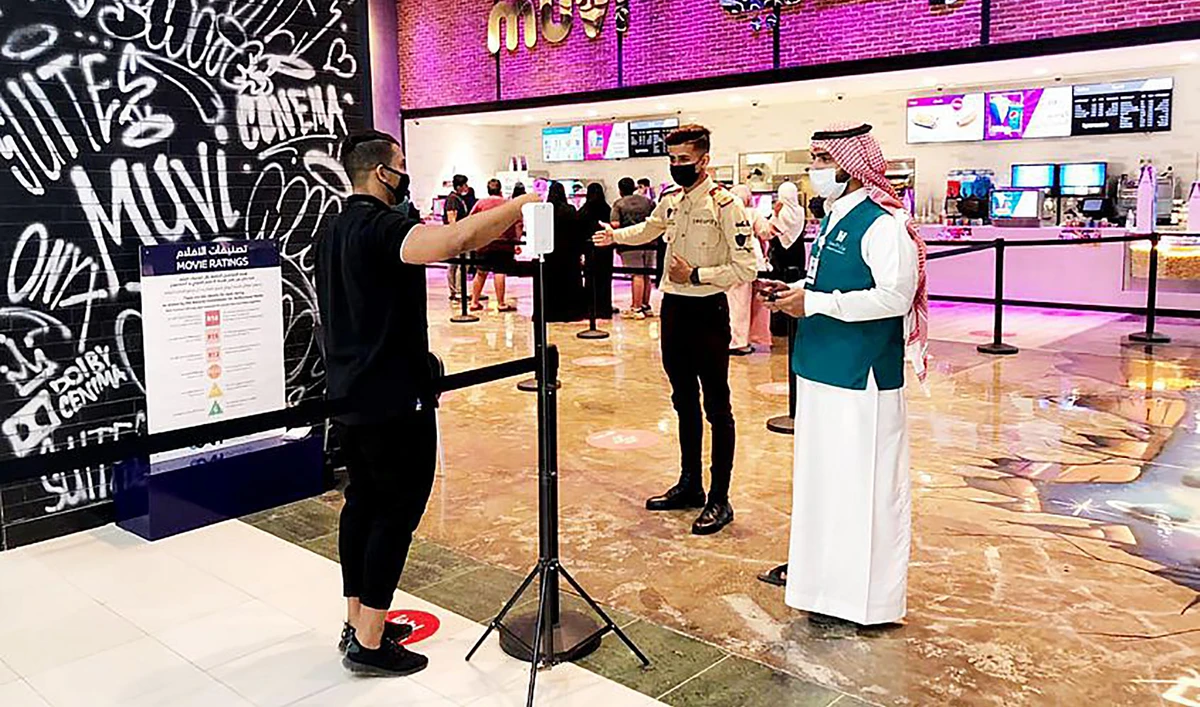 This photograph released by Saudi Press Agency on August 21, 2021, shows officials checking temperature of a man at the entrance of a movie theater in Saudi Arabia. (SPA)