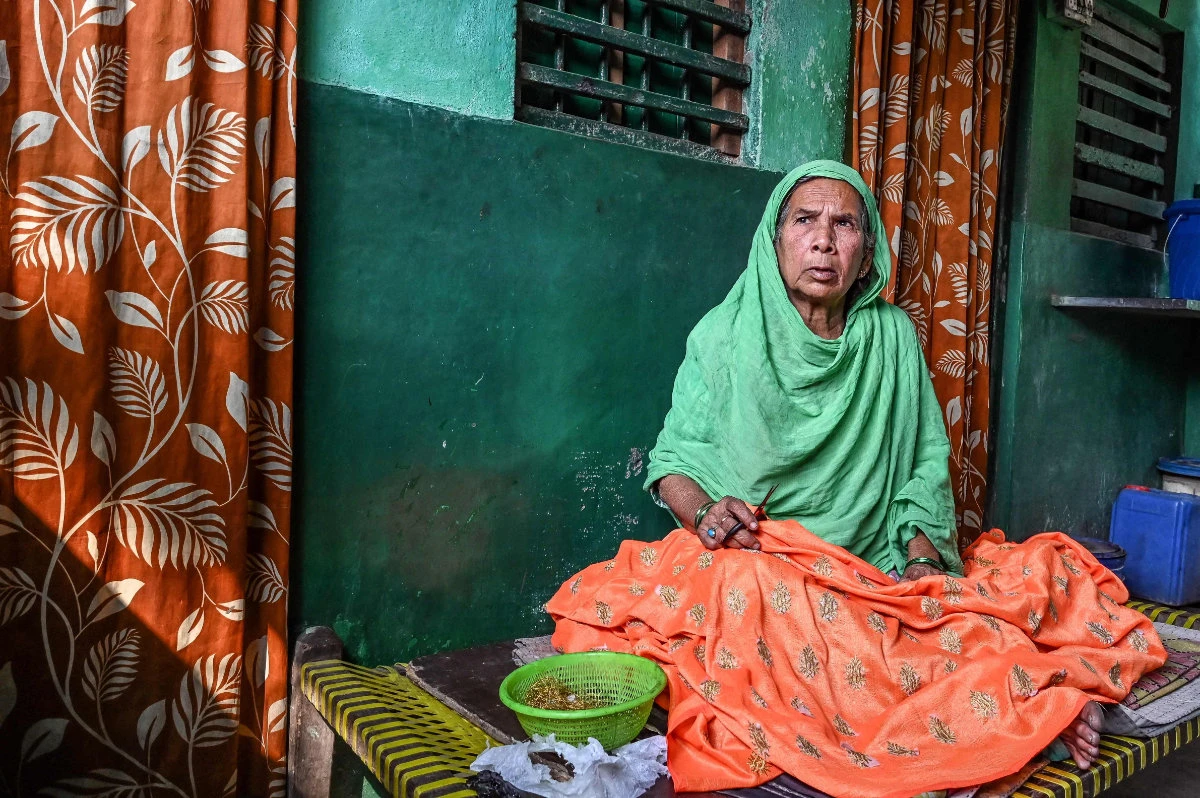 Sultana Begum works on a garment inside her house in Kolkata. (Photo by Dibyangshu Sarkar / AFP)